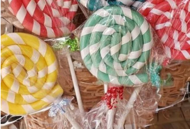 DIY giant lollipops made from pool noodles wrapped in cellophane for a Candy Land party decoration.
