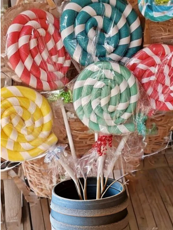 DIY giant lollipops made from pool noodles wrapped in cellophane for a Candy Land party decoration.