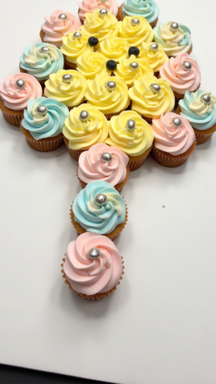 Baby rattle pull-apart cupcake cake decorated with yellow, pink, and blue frosting rosettes
