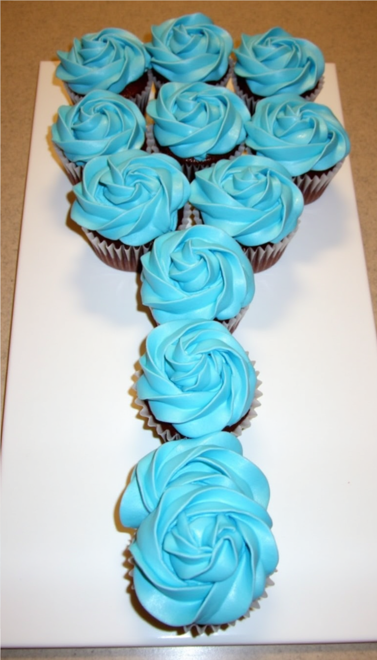 Blue baby rattle cupcake cake on a board, perfect for boy baby showers