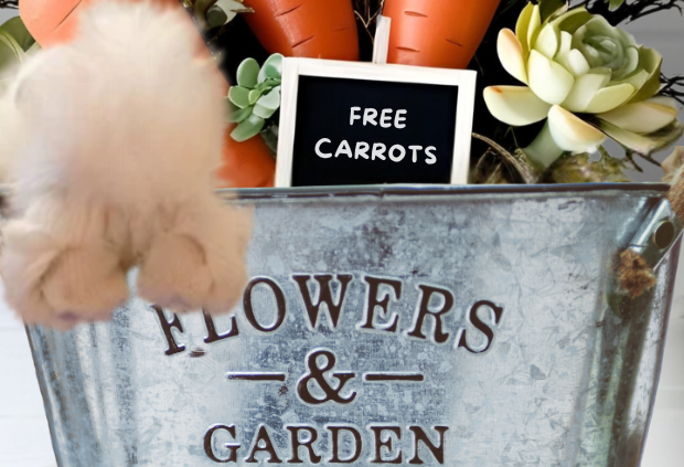 Easter bunny centerpiece with faux carrots, spring florals, and a 'Free Carrots' sign in a rustic garden bucket.