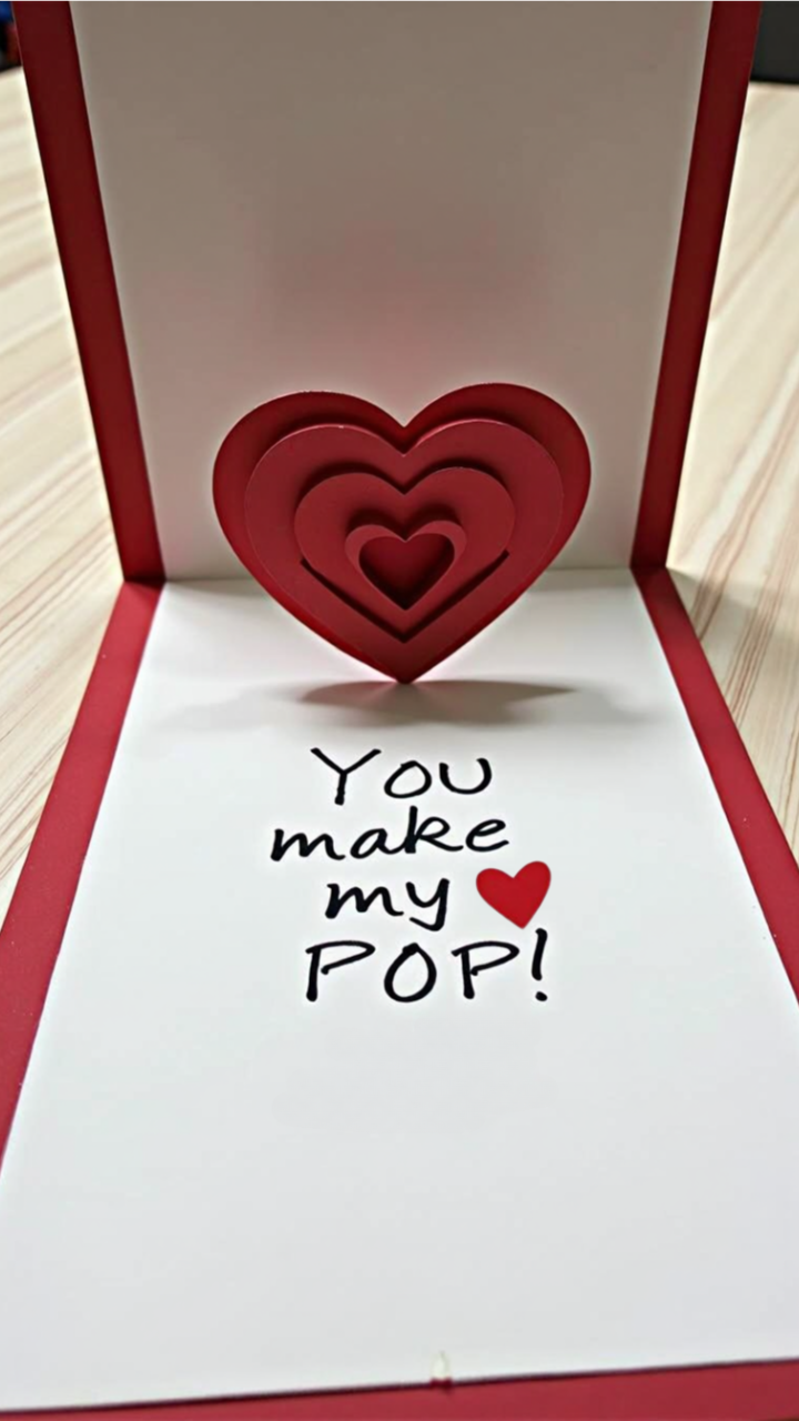 DIY 3D Valentine’s Day card with layered red pop-up hearts and the message “You make my heart pop!” inside 
