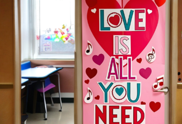 Valentine's Day-themed door decoration with a large pink and red heart, musical notes, and the phrase 'LOVE IS ALL YOU NEED' in bold, colorful letters.