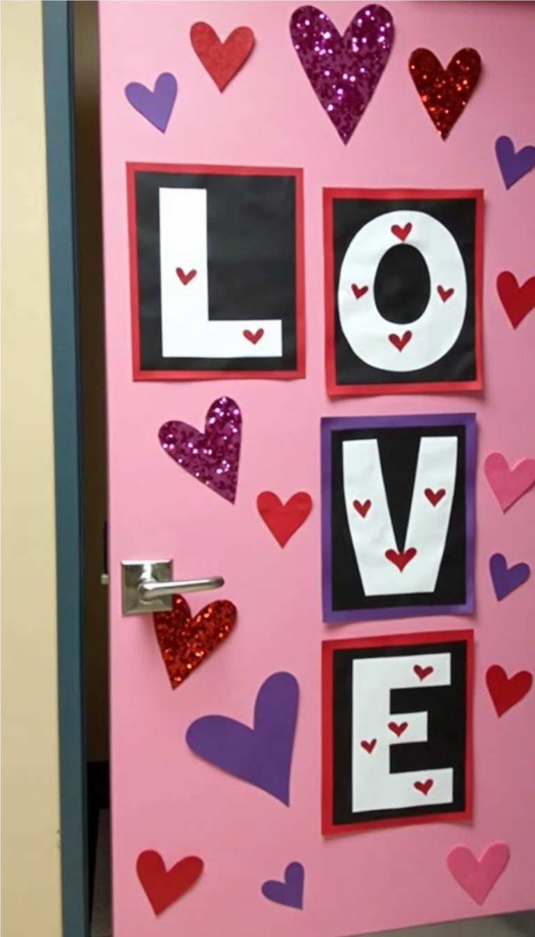 Pink classroom door decorated with large 'LOVE' letters and glittery hearts for Valentine's Day.